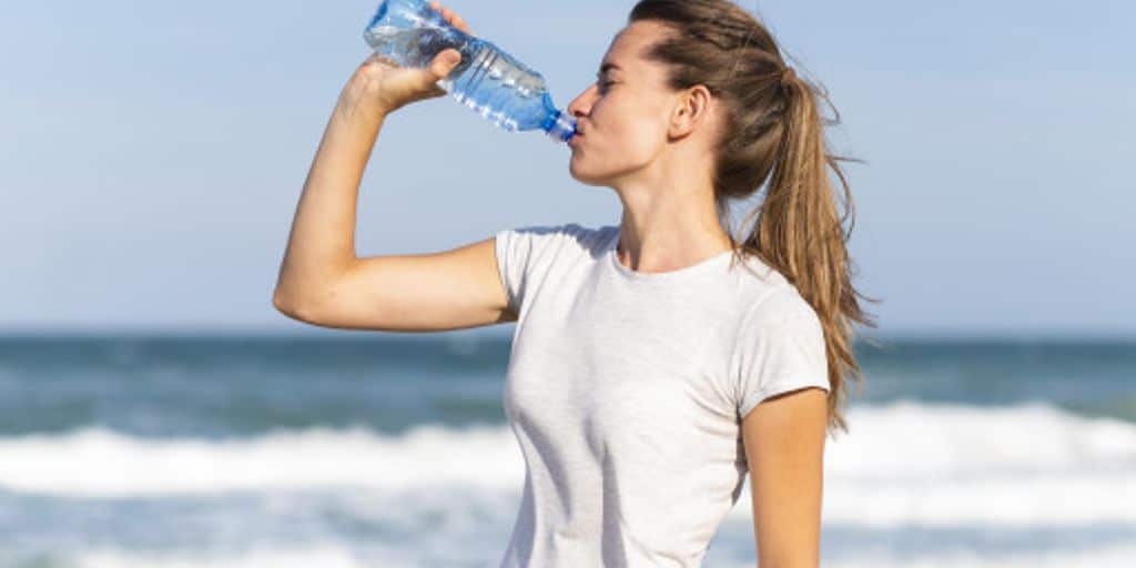 person drinking water in a sunny park